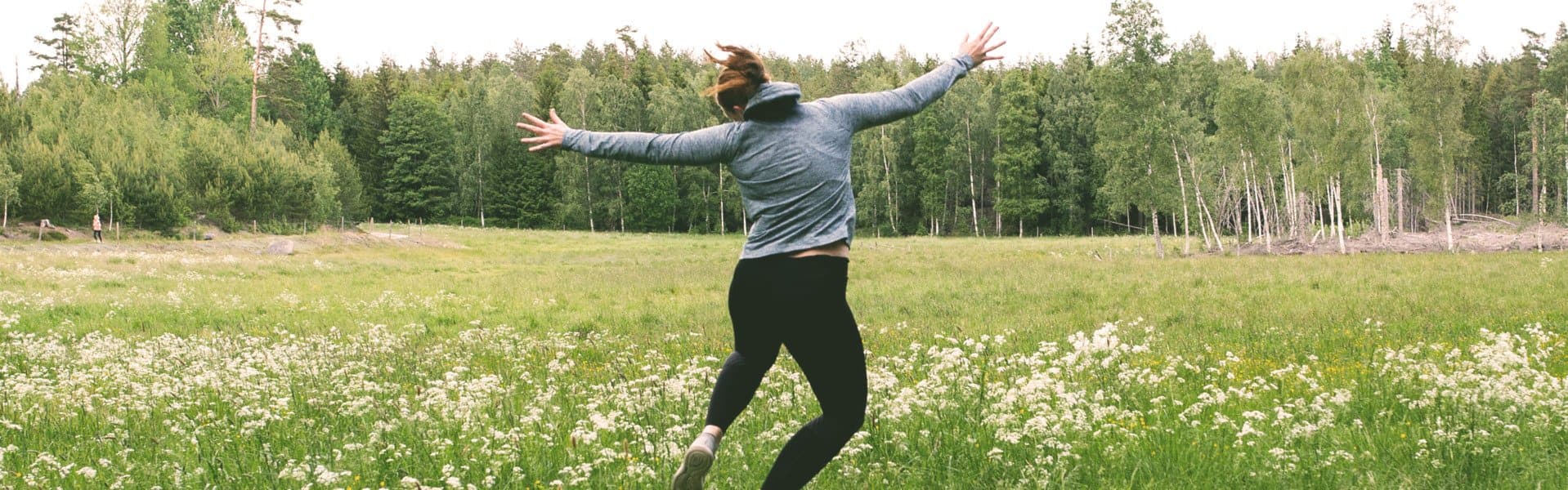 Kvinna hoppar på grönskande äng