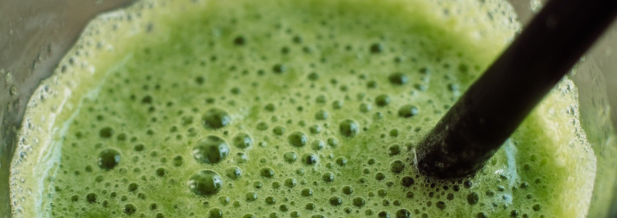 Person dricker den gröna smoothien som just mixats Person dricker den gröna smoothien som just mixats