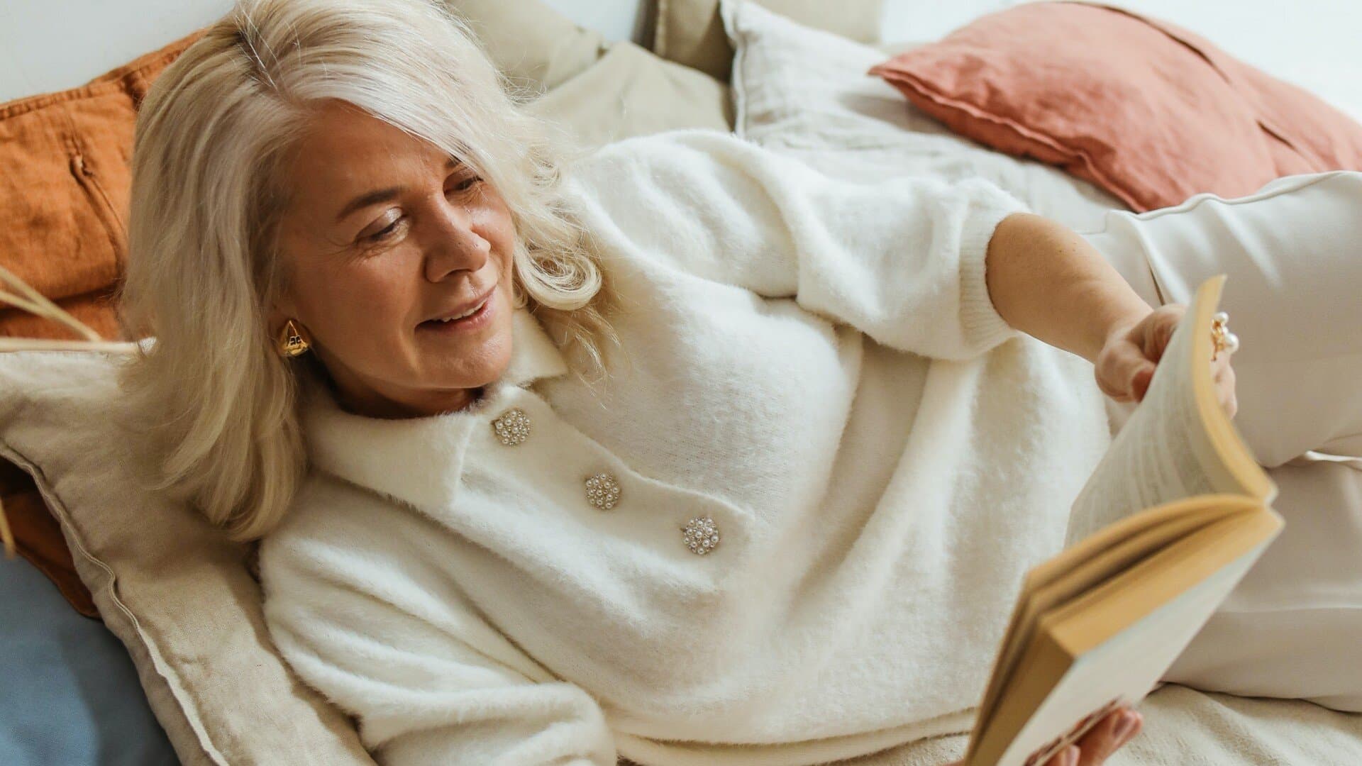 Kvinna ligger i sängen och läser bok Kvinna ligger i sängen och läser bok