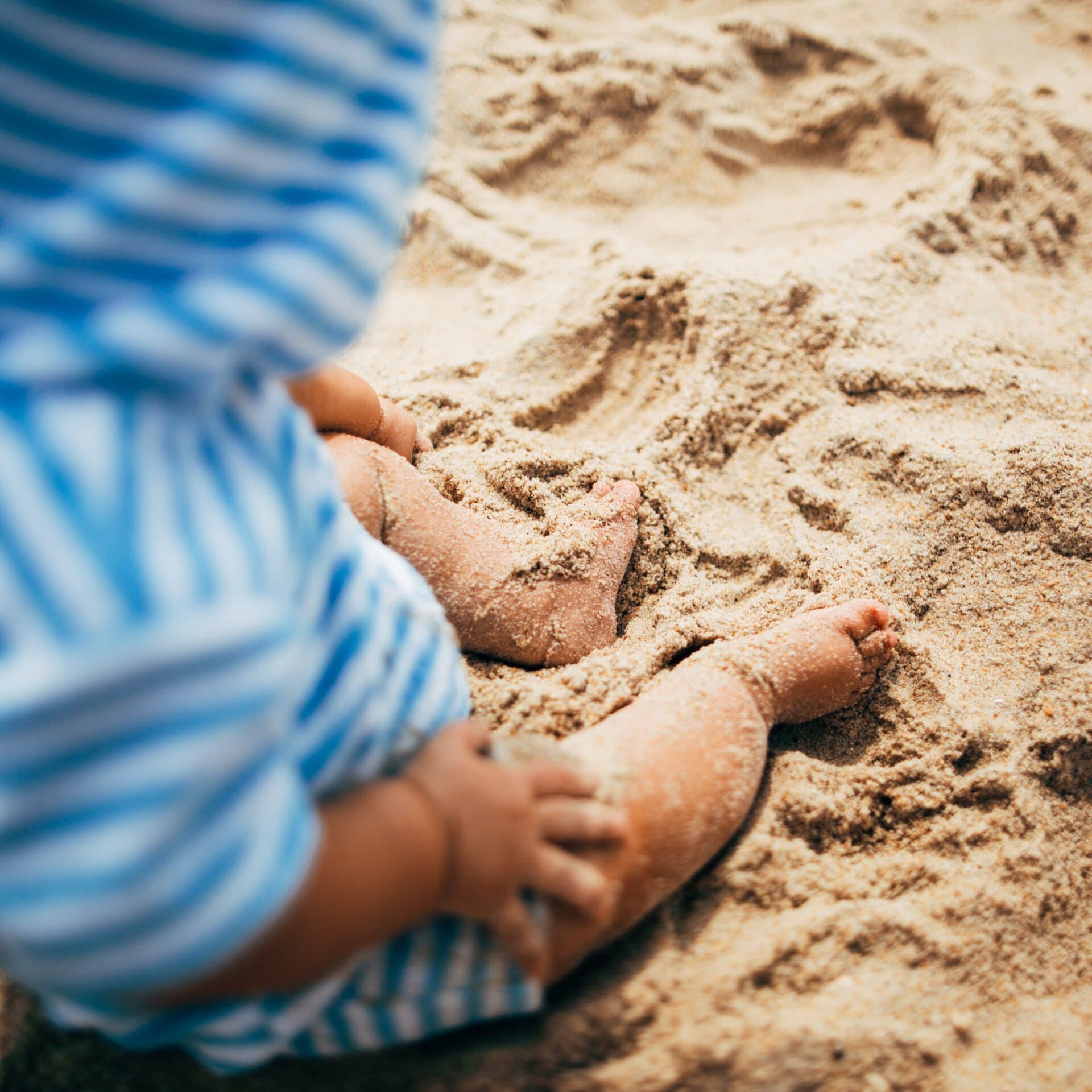 Barn sitter på en sandstrand Barn sitter på en sandstrand