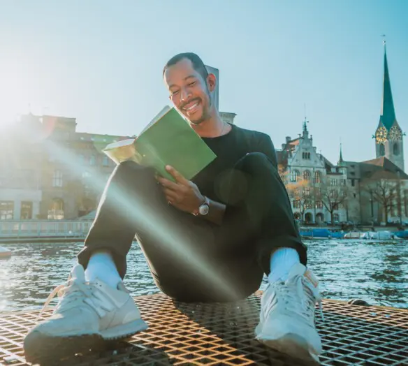 Man sitter i solen och läser en bok