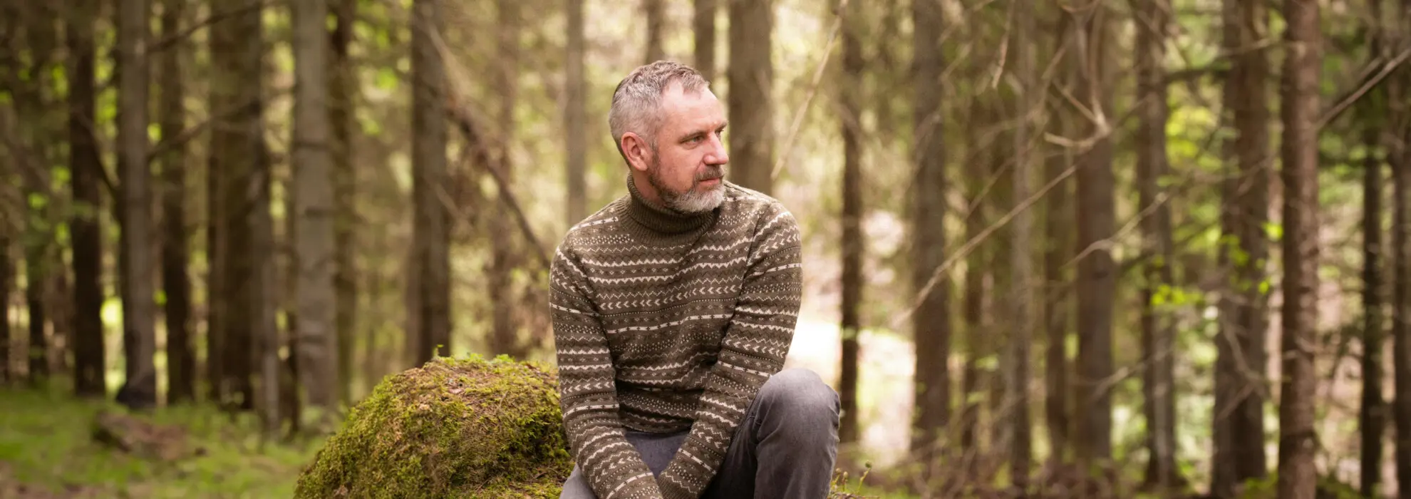 Man sitter i skogen med hund