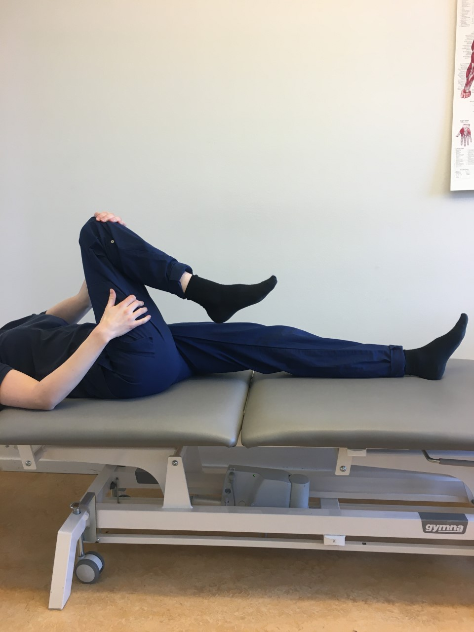 Person ligger p&aring; brits, ena benet rakt, andra benet b&ouml;jt upp halvv&auml;gs mot magen. en hand vid l&aring;ret, den andra &ouml;ver kn&auml;t. 