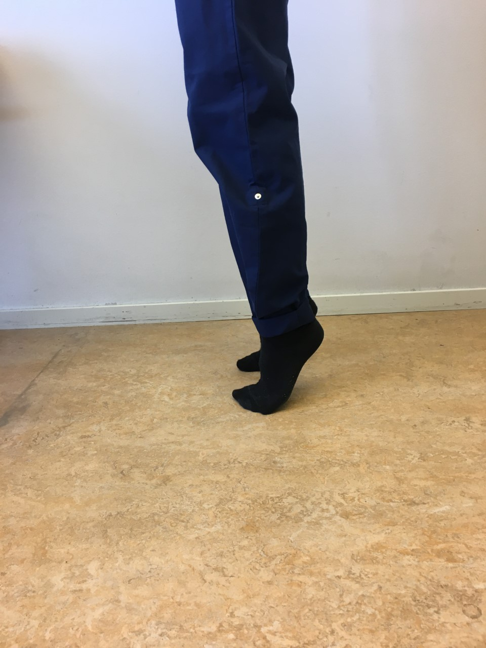 Person g&ouml;r t&aring;h&auml;vning med b&aring;da f&ouml;tterna, h&auml;larna l&auml;mnar golvet. 