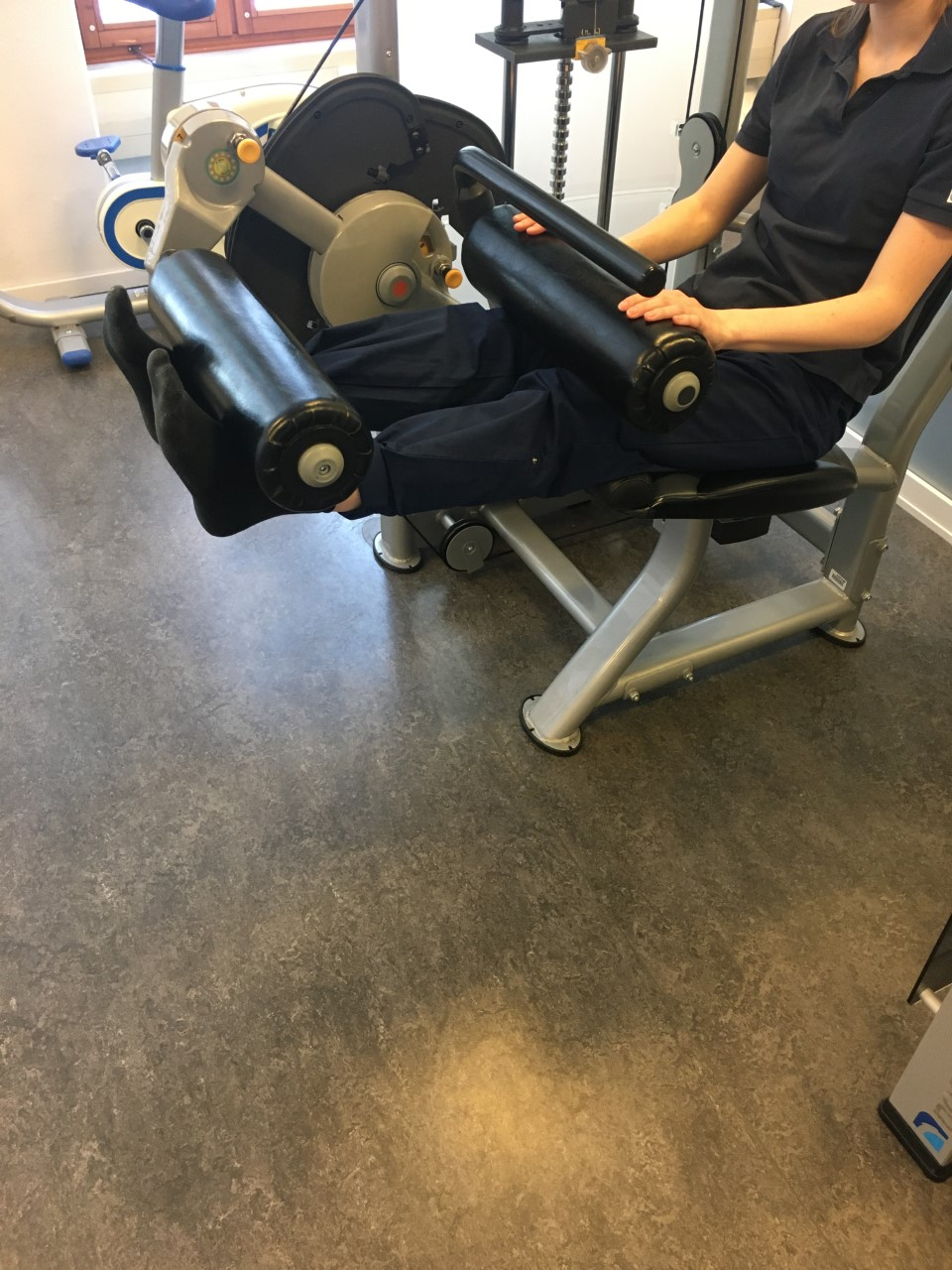 Benstr&auml;ck i maskin, utstr&auml;ckta ben. F&ouml;tterna under fotrullen.