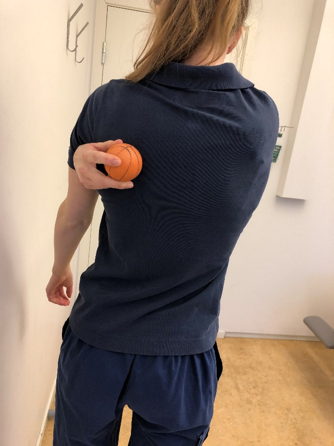 Tjej h&aring;ller boll mot skulderbladet.