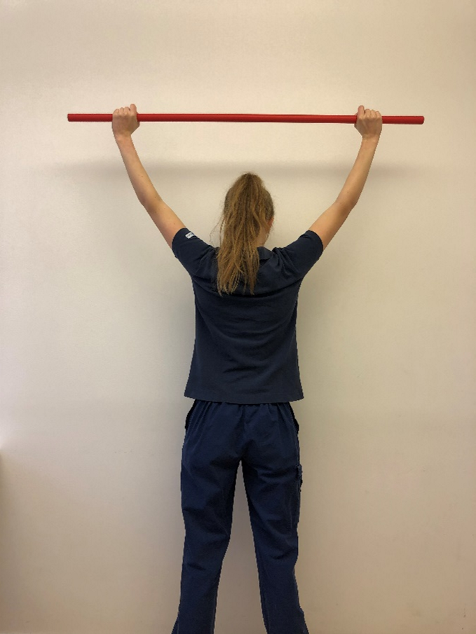 R&ouml;rlighet &ouml;vning 3.1.pngTjej st&aring;r och h&aring;ller st&aring;ng med str&auml;ckta armar ovanf&ouml;r huvudet.