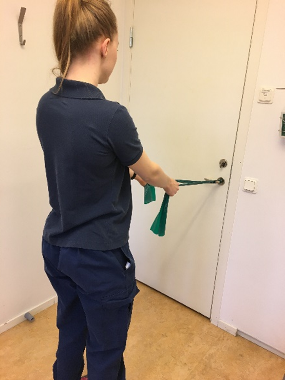 Tjej h&aring;ller i varje ende av gummiband med b&aring;da armar str&auml;ckta. Gummibanden sitter, i mitten, fast i ett d&ouml;rrhandtag.