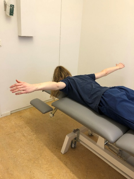 Tjej ligger p&aring; mage p&aring; en brist och lyfter raka armarna rakt ut fr&aring;n kroppen.