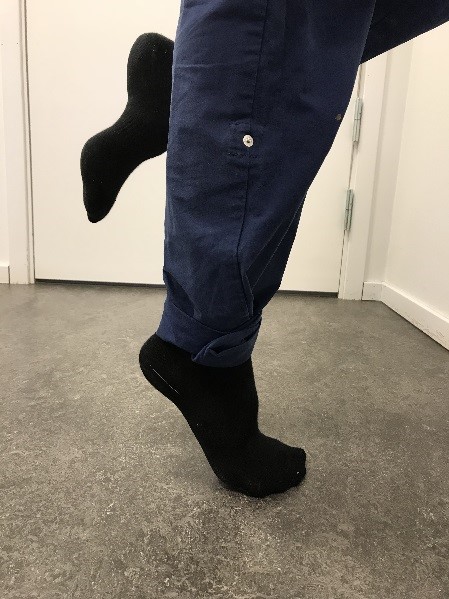 T&aring;h&auml;vning p&aring; golv. Ena benet b&ouml;jt och i luften, andra benets fot har t&aring;rna i golvet och h&auml;len dras upp&aring;t.