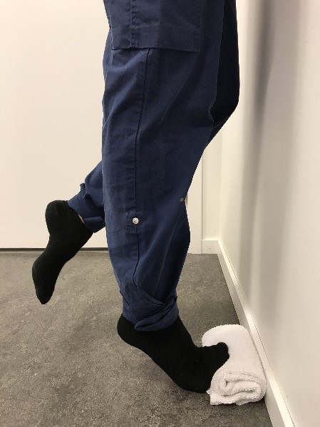 Tåhävning mot hoprullad handduk, hälen dras uppåt. Det andra benet är lätt böjt vid knät.