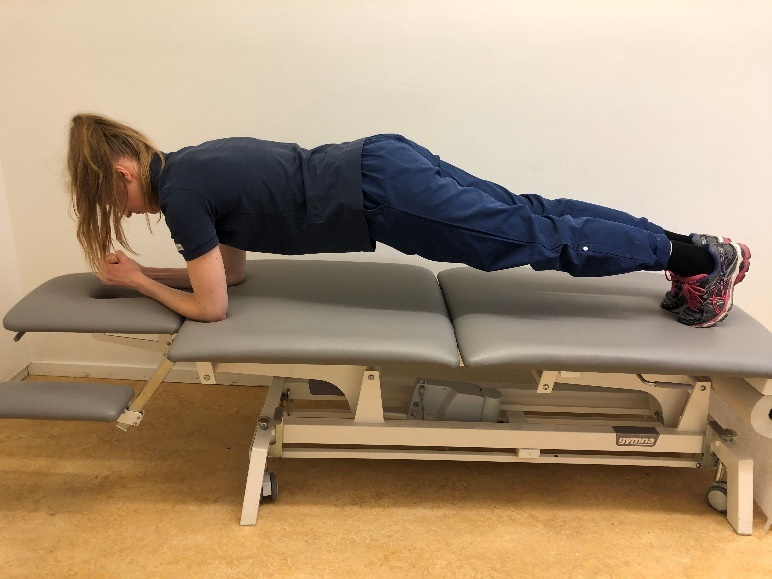 Tjej p&aring; brist med rak kropp st&aring;ende p&aring; underarmarna och t&aring;rna i britsen.