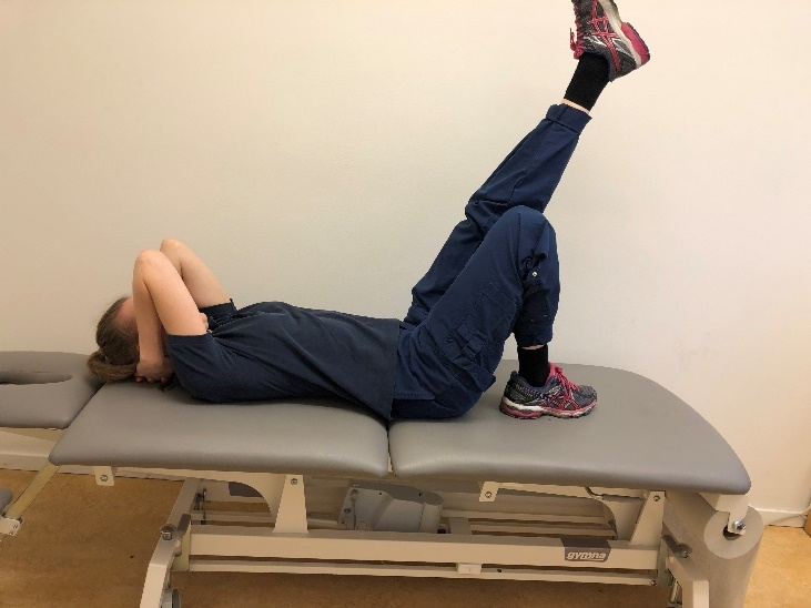 Tjej liggandes med rygg p&aring; brits med h&auml;nderna bakom nacken. Ena benet upp snett upp mot taket och andra med uppdragen fot.