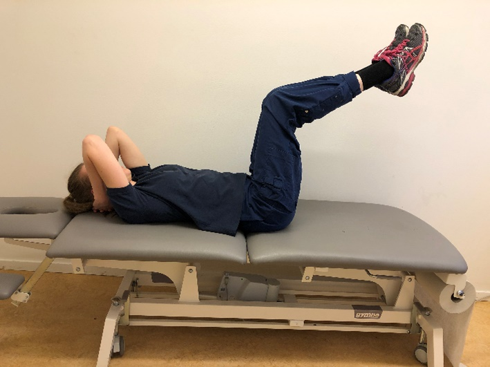 Tjej nu med b&aring;da benen i luften och h&auml;nderna fortsatt bakom nacken.