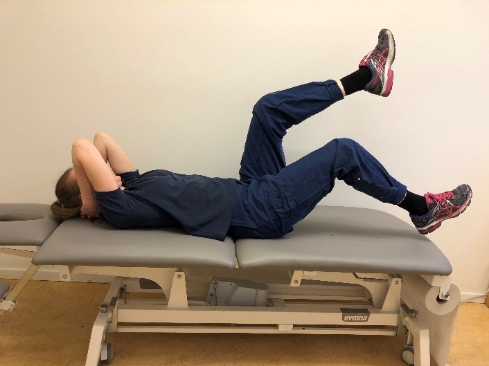 Tjej på brits med båda benen i luften där ena benet är lägre mot bristen än det andra.