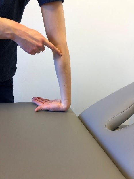 Person st&aring;r vid brits och lutar handryggen platt mot underlaget. 